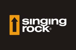 Logotyp czeskiego prducenta sprzętu firmy Singing Rock. Logo na czarnym tle przedstawia czarną strzałkę skierowaną ku górze wpisaną w żółty kwadrat znajdujący się po lewej stronie i napisu w dwóch wierszach Singing Rock w kolorze czarnym.