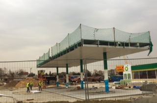 Zdjęcie przedstawia stacje benzynowa w budowie na dachu której, zainstalowano zabezpieczenie w postaci siatką ochronnej uniemożliwiającej na upadek z wysokości pracownika.