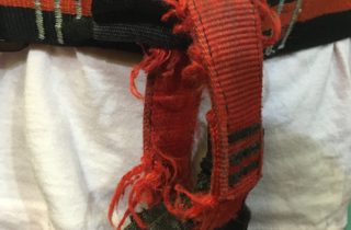 Uprząż wspinaczkowa, która jest w znacznym stopniu uszkodzona. Na uwagę zasługuje łącznik, który posiada liczne poszarpane włókna, ekstremalnie zmniejszające wytrzymałość.