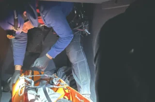 Ratownik w kasku i uprzęży wykonuje ewakuację osoby na noszach w przestrzeni zamkniętej