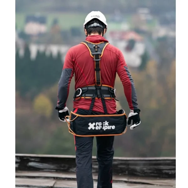 Alpinista przemysłowy z ławką Rock Empire Ledge podczas pracy na wysokości